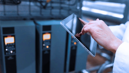 Zdjęcie dłoni osoby, która trzyma tablet i zarządza za jego pomocą procesami produkcyjnymi.